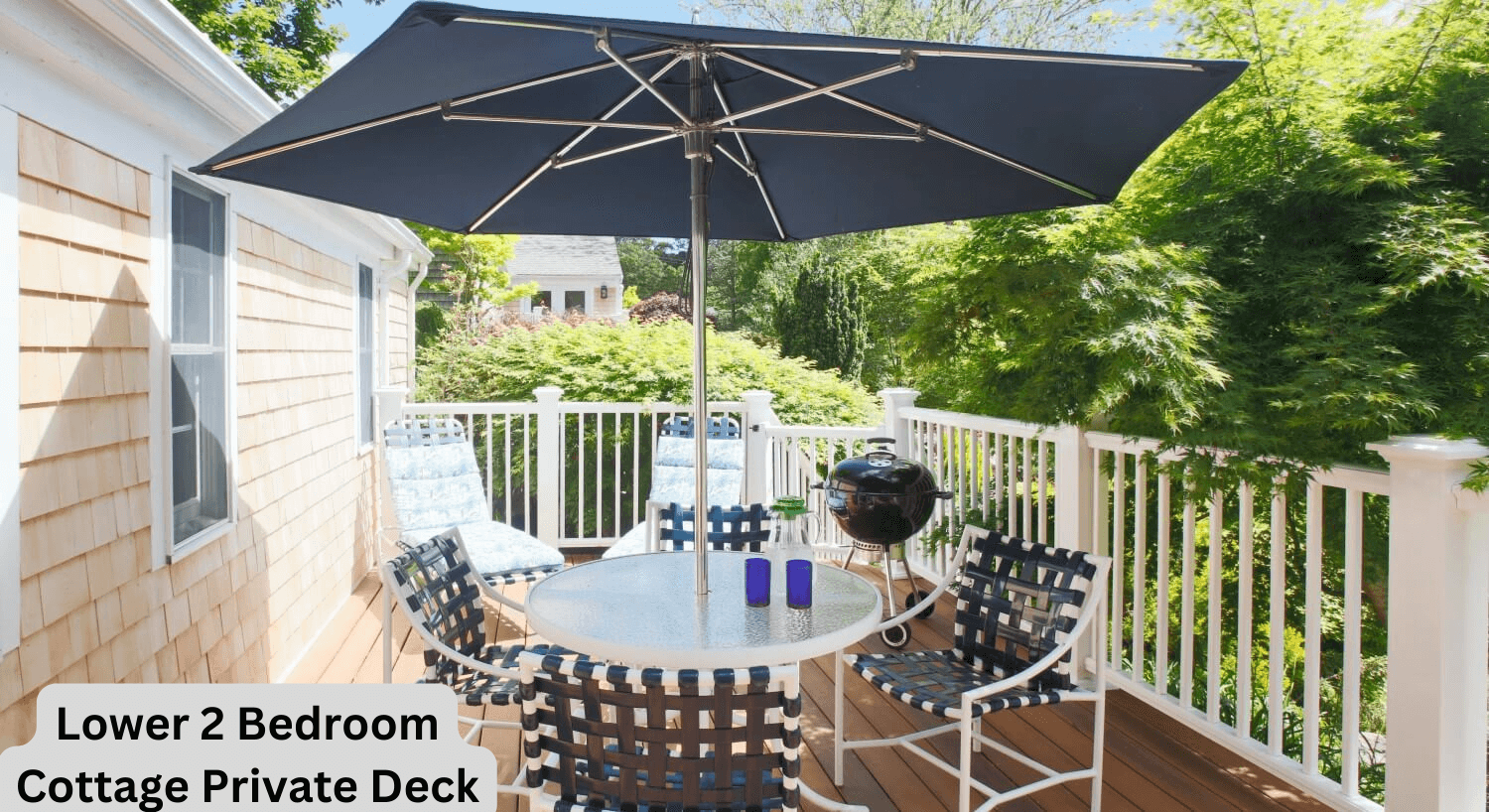 Lower Two Bedroom Cottage private outdoor deck with deck furniture under an umbrella overlooking gardens. 
